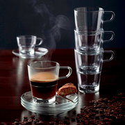 Espressotasse Senso 70ml mit dampfendem Espresso, von vorne fotografiert, auf einem Tisch mit Kaffeebohnen und einem Keks auf der Untertasse.