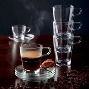 Espressotasse Senso 70ml mit dampfendem Espresso, von vorne fotografiert, auf einem Tisch mit Kaffeebohnen und einem Keks auf der Untertasse.