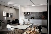 Moderne Küche mit grauem Marmor-Backsplash und drei hängenden Schienenpendelleuchten in Kugelform, Perspektive von der Seite.