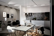 Moderne Küche mit grauem Marmor-Backsplash und drei hängenden Schienenpendelleuchten in Kugelform, Perspektive von der Seite.