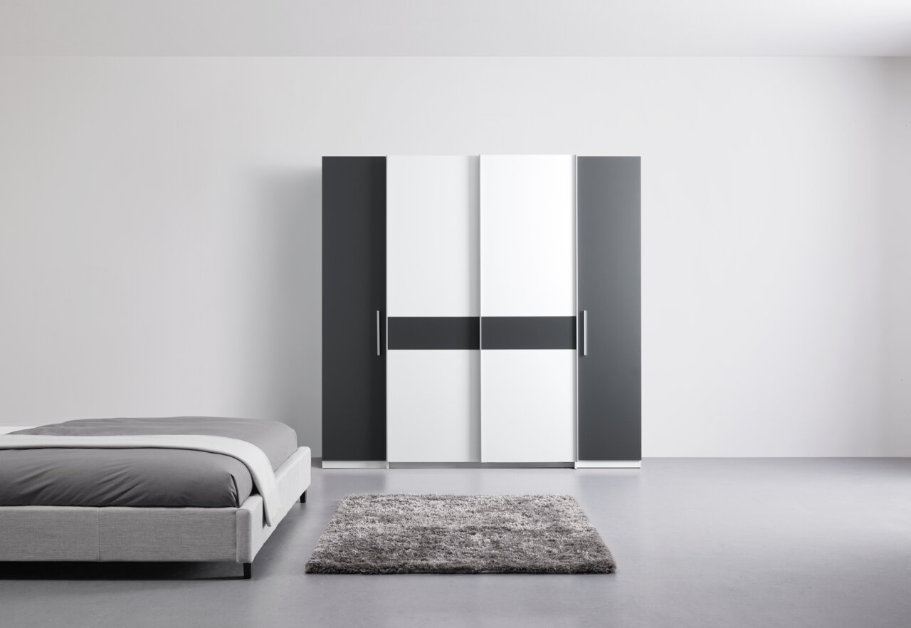 Moderne draai- en schuifdeurkast met vier deuren in een zwart-wit ontwerp, hier afgebeeld in een minimalistische slaapkamer.