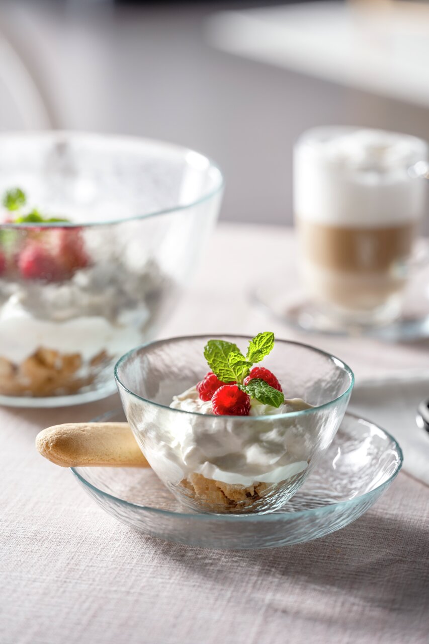 Glazen schaal Attivo 12 cm met dessert, versierd met frambozen en munt, gefotografeerd vanuit een zijaanzicht.