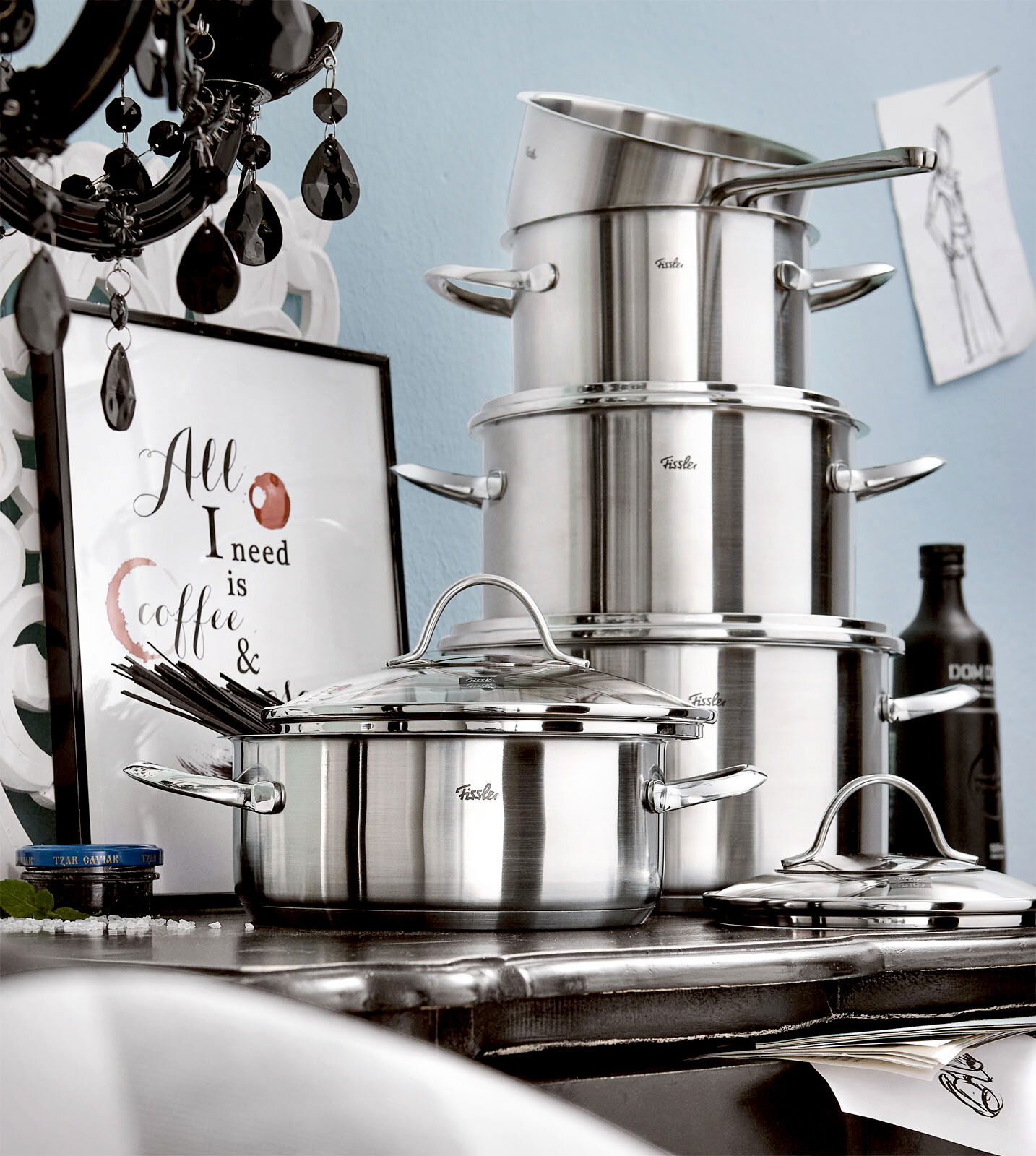 Topfset Paris 5-tlg. aus Edelstahl, seitliche Perspektive, gestapelt auf einem Tisch mit dekorativem Hintergrund.