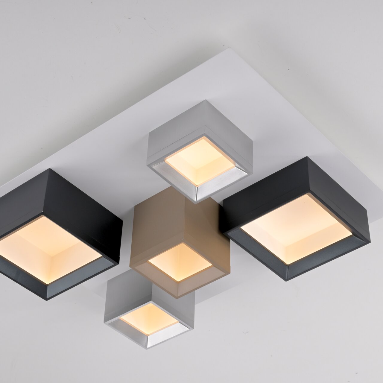 Moderne led-plafondlamp met vier vierkante lichtelementen in verschillende kleuren, gefotografeerd vanuit vogelperspectief.