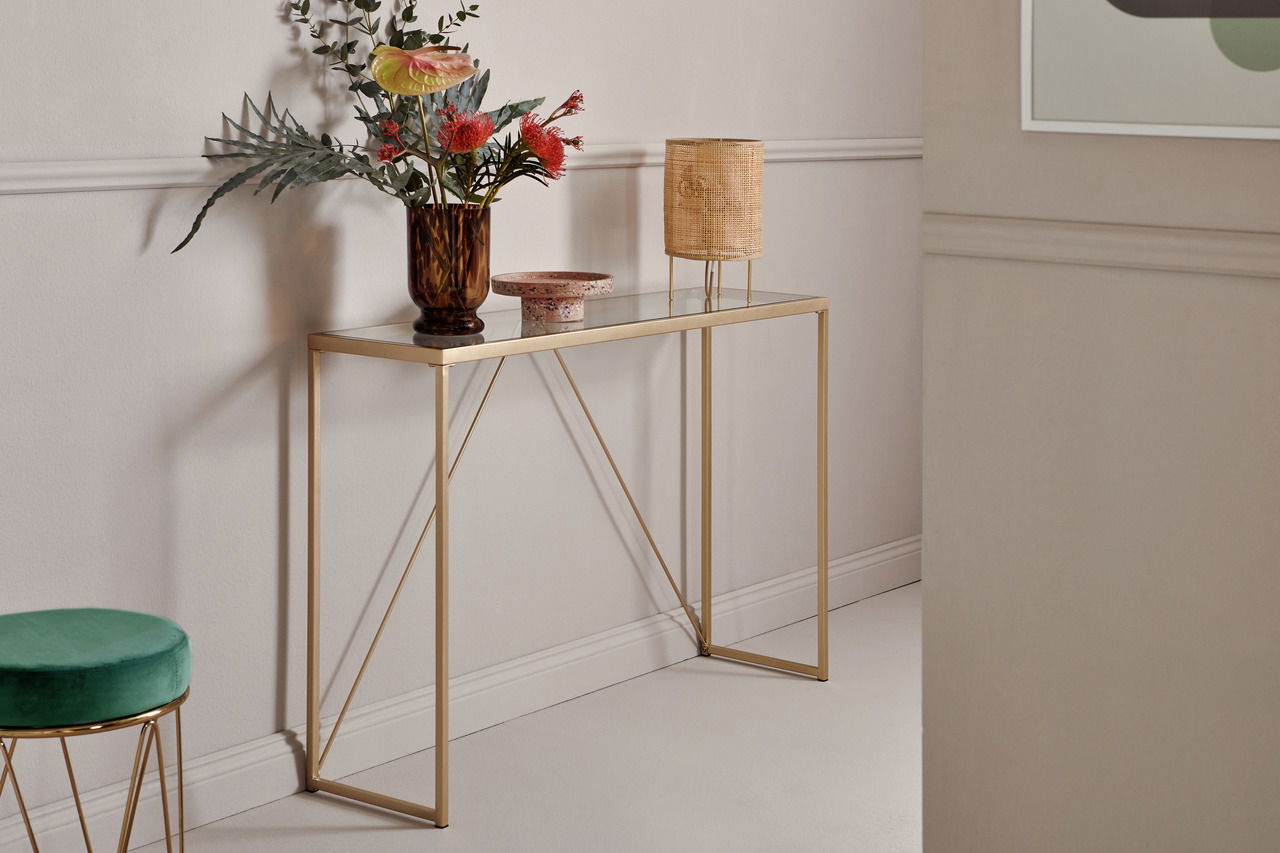 Elegante Konsole mit goldfarbenem Gestell und Glasplatte, dekoriert mit einer Vase und Lampe, seitliche Perspektive.