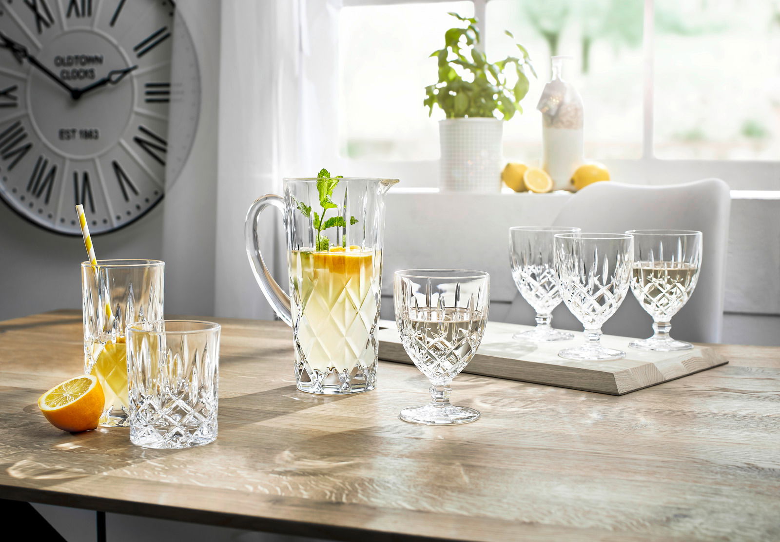 Elegantes Krugset Noblesse 5-tlg. auf einem Tisch, mit einem Krug und Gläsern aus Kristallglas, gefüllt mit Getränken, in einem hellen Raum mit Blick auf ein Fenster.