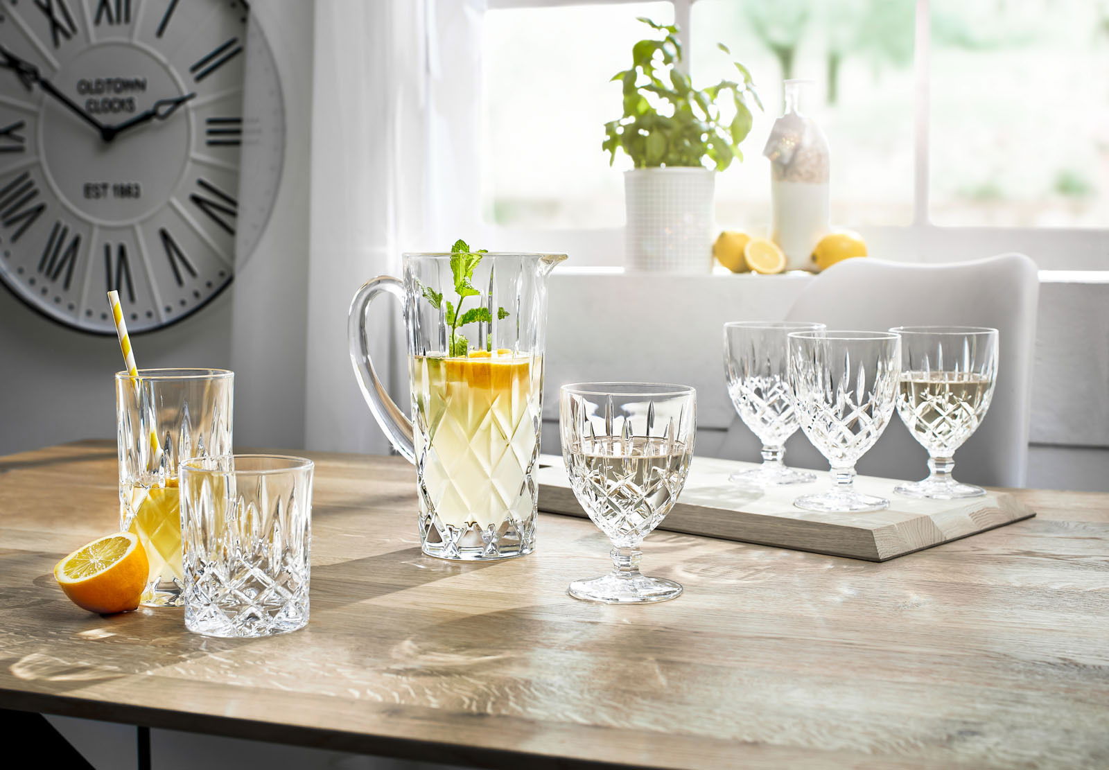 Elegantes Krugset Noblesse 5-tlg. auf einem Tisch, mit einem Krug und Gläsern aus Kristallglas, gefüllt mit Getränken, in einem hellen Raum mit Blick auf ein Fenster.