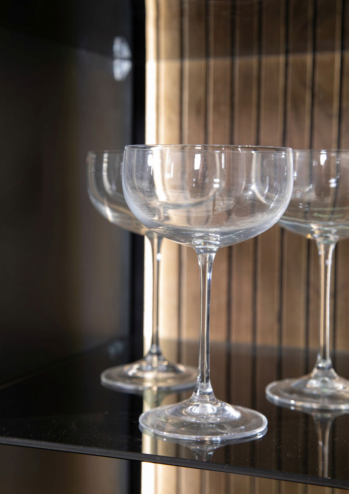 Nahaufnahme von eleganten Weingläsern in einem Highboard, seitliche Perspektive