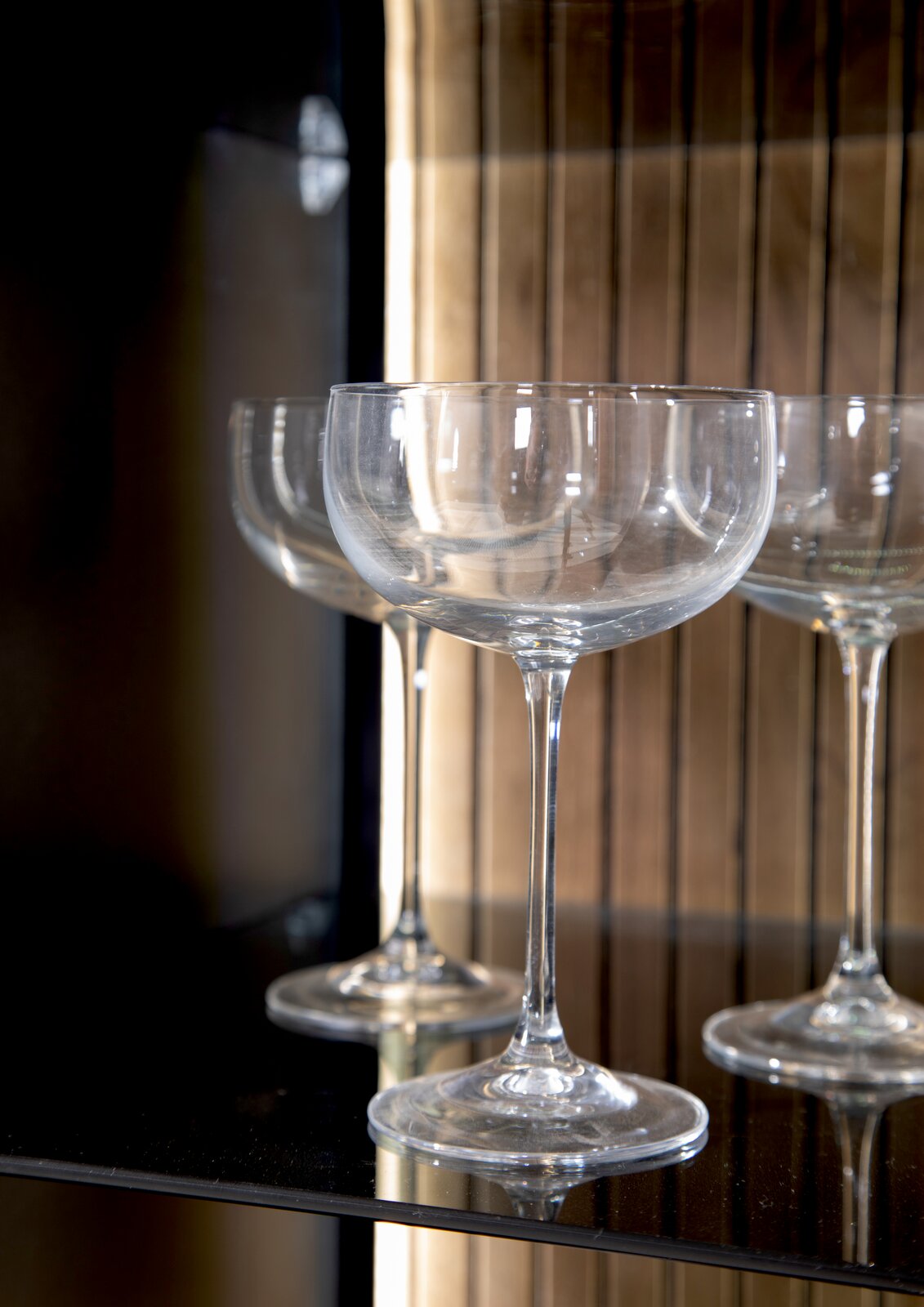 Nahaufnahme von eleganten Weingläsern in einem Highboard, seitliche Perspektive