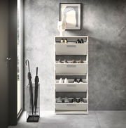 Moderner Schuhkipper mit vier Klappen, frontal fotografiert, in einem stilvollen Eingangsbereich mit grauer Wand und Regenschirmständer.