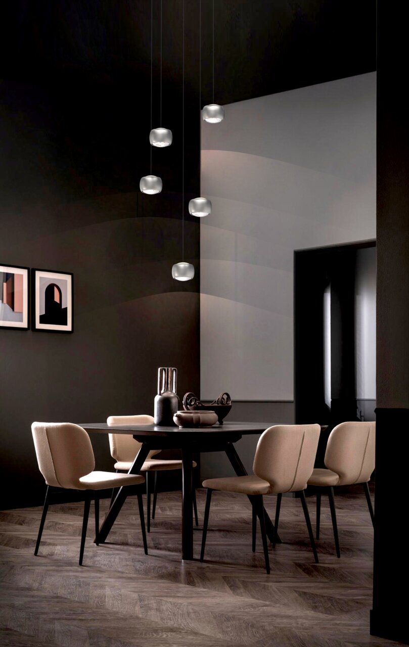 Moderne LED-Pendelleuchte in einem stilvollen Esszimmer, von unten betrachtet, mit mehreren hängenden Leuchten über einem runden Tisch mit eleganten Stühlen.