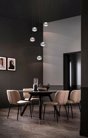 Moderne LED-Pendelleuchte in einem stilvollen Esszimmer, von unten betrachtet, mit mehreren hängenden Leuchten über einem runden Tisch mit eleganten Stühlen.