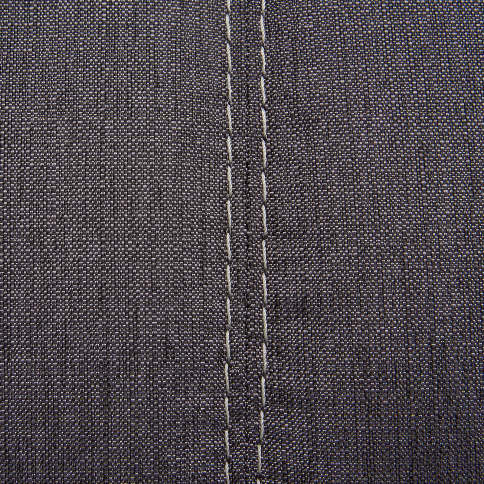 Nahaufnahme einer grauen Stoffoberfläche mit sichtbaren Nähten, perspektivisch von oben betrachtet.