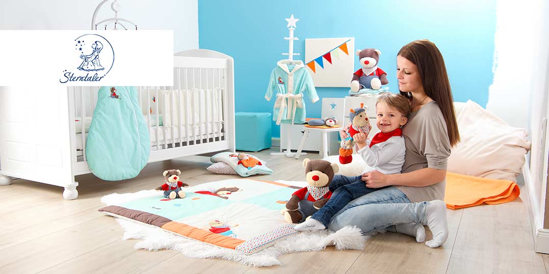 Kinderzimmer mit Mutter und Kind, Babybett und Spielzeug der Marke Sterntaler