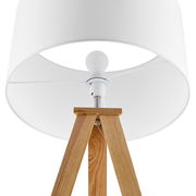 Nahaufnahme einer Stehleuchte mit weißem Lampenschirm und dreibeinigem Holzgestell, von unten betrachtet.