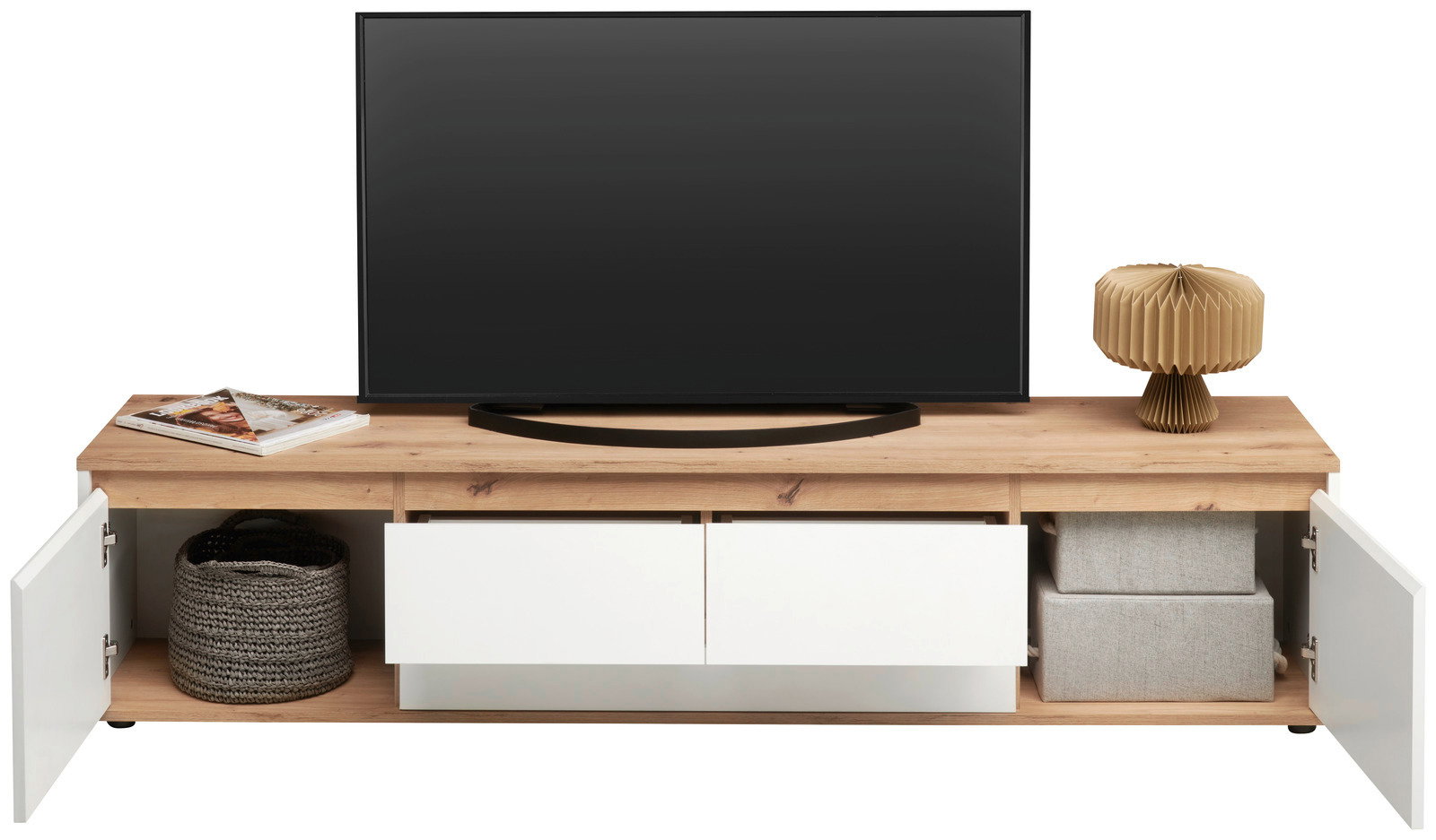 Frontale Ansicht eines XL-TV-Lowboards mit Holzoberfläche, zwei offenen Schubladen und seitlichen Fächern mit Türen. Dekoriert mit einem Fernseher, einer Lampe und Körben.