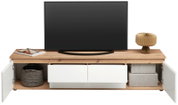Frontale Ansicht eines XL-TV-Lowboards mit Holzoberfläche, zwei offenen Schubladen und seitlichen Fächern mit Türen. Dekoriert mit einem Fernseher, einer Lampe und Körben.
