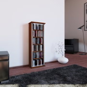 Schmales CD-/DVD-Regal in dunkler Holzoptik mit silberfarbenen Seitenteilen, frontale leicht seitliche Perspektive, freistehend an einer weißen Wand im Wohnzimmer neben schwarzem Sessel und weißer Bodenvase.