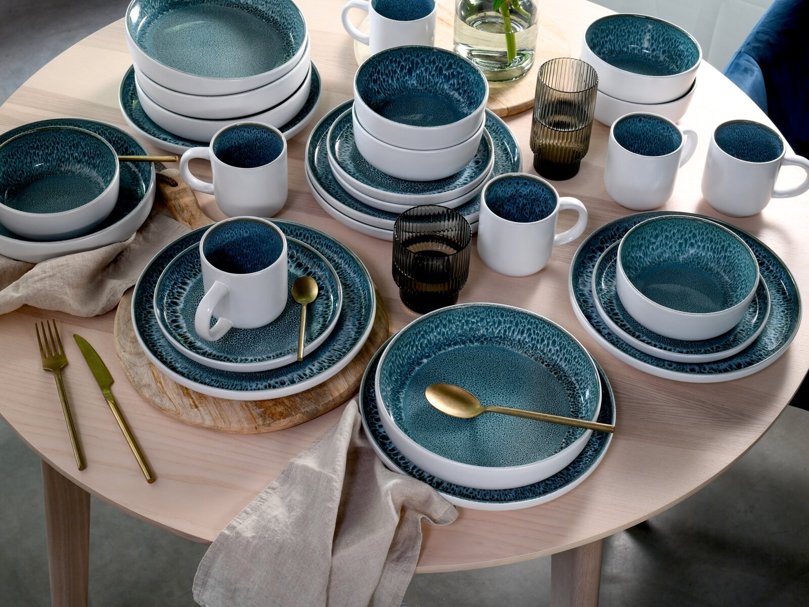 Kombiservice 16-delig, ijsblauw, op een tafel, bestaande uit borden, schalen en kopjes in een elegant ijsblauw ontwerp, gefotografeerd van bovenaf.