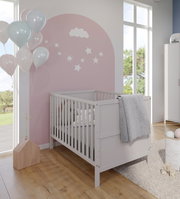 Babybett in einem hellen Kinderzimmer mit rosa Wand und Wolken- und Sternendekoration, seitliche Perspektive