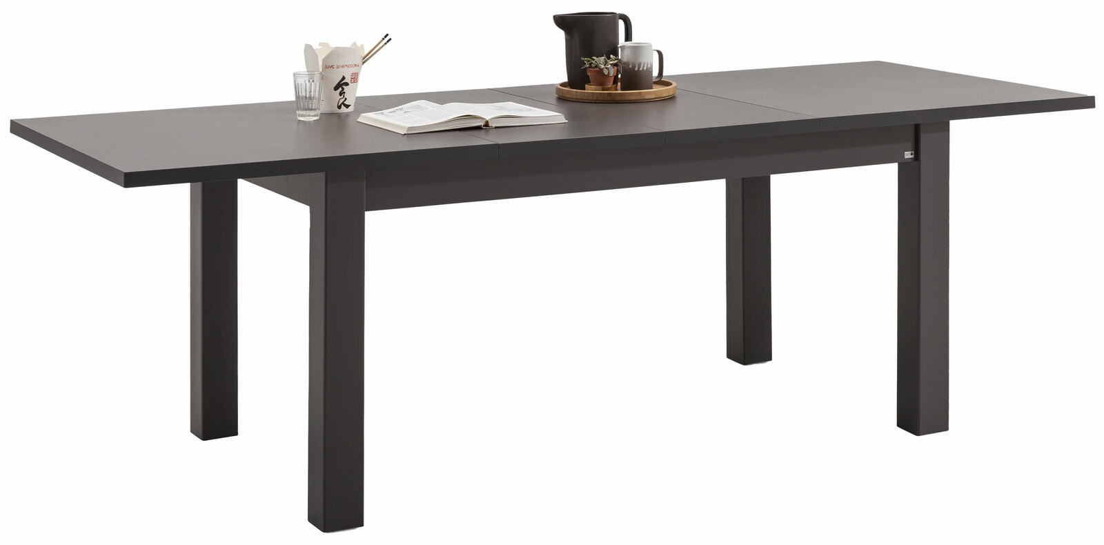 Moderner, ausziehbarer Esstisch in dunkler Farbe, seitliche Perspektive, dekoriert mit Geschirr und Pflanzen.