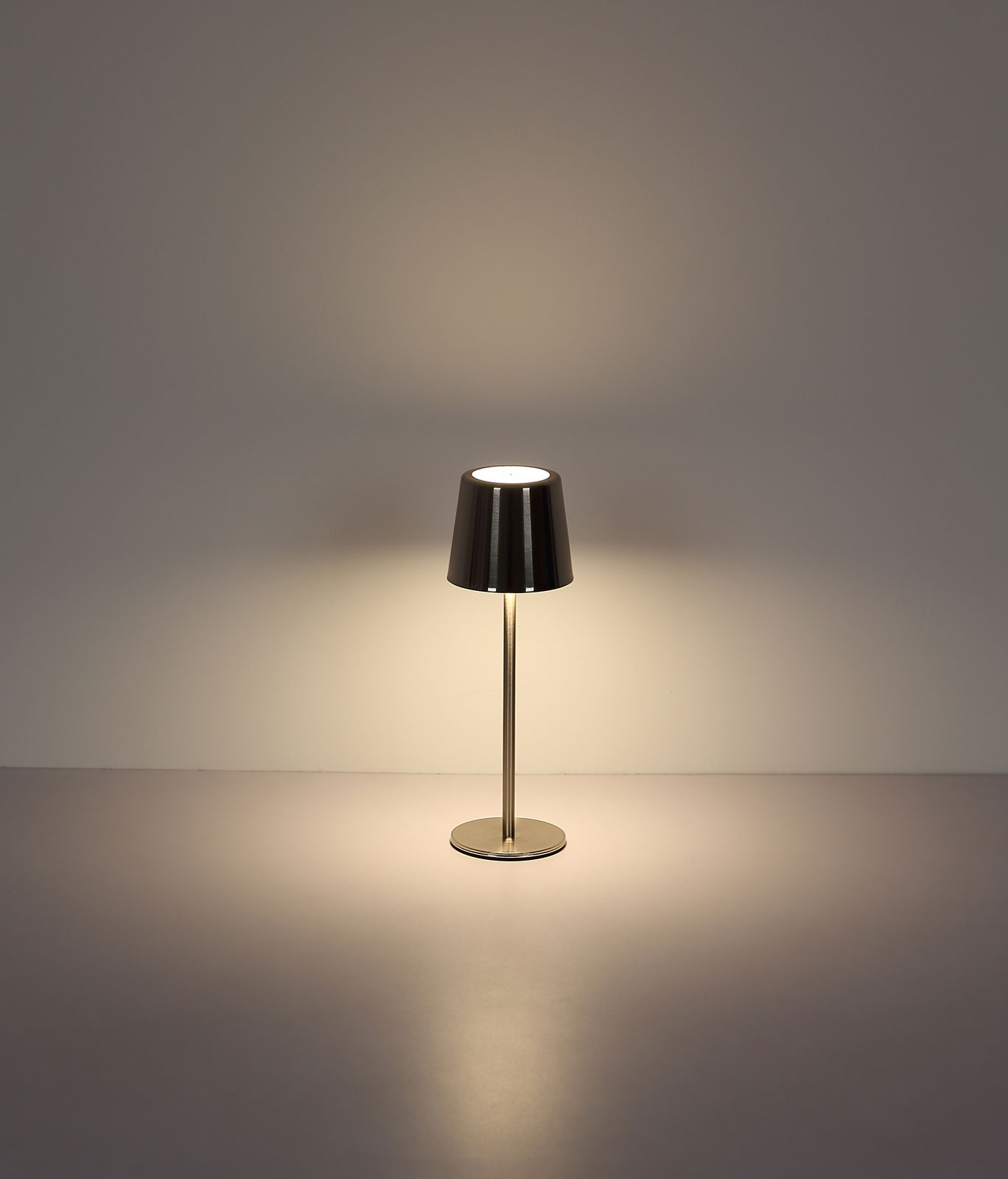 Moderne Tischleuchte mit metallischem Schirm, frontal beleuchtet auf neutralem Hintergrund