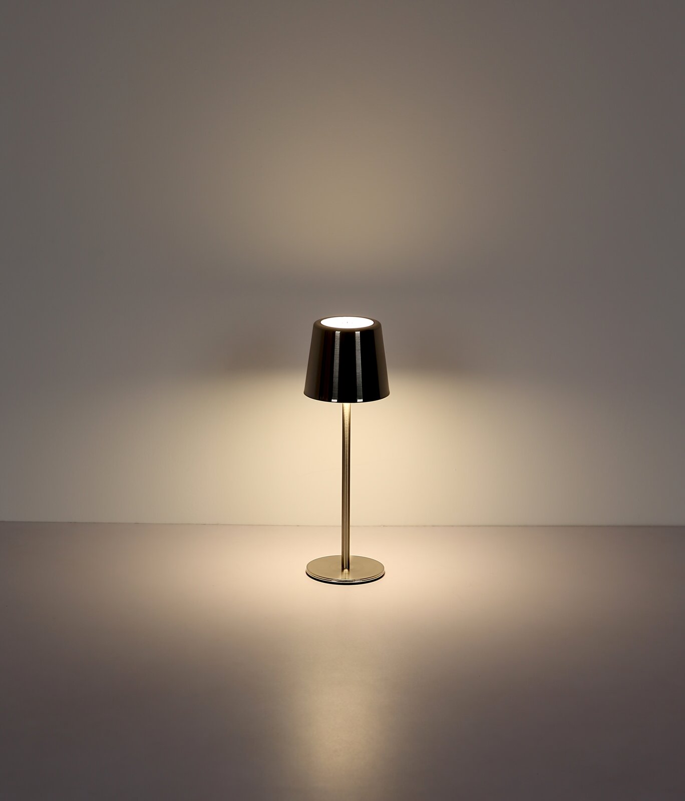 Moderne Tischleuchte mit metallischem Schirm, frontal beleuchtet auf neutralem Hintergrund