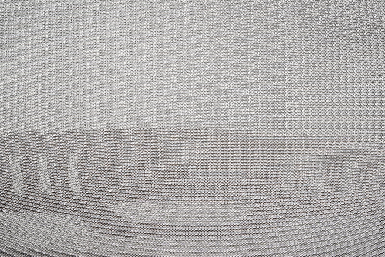 Nahaufnahme eines grauen Netzstoffs mit strukturiertem Muster, vermutlich Teil eines Drehstuhls, von vorne betrachtet.