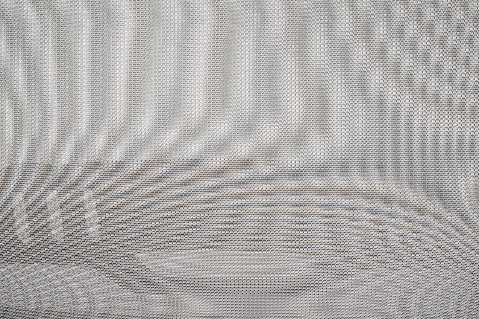 Nahaufnahme eines grauen Netzstoffs mit strukturiertem Muster, vermutlich Teil eines Drehstuhls, von vorne betrachtet.