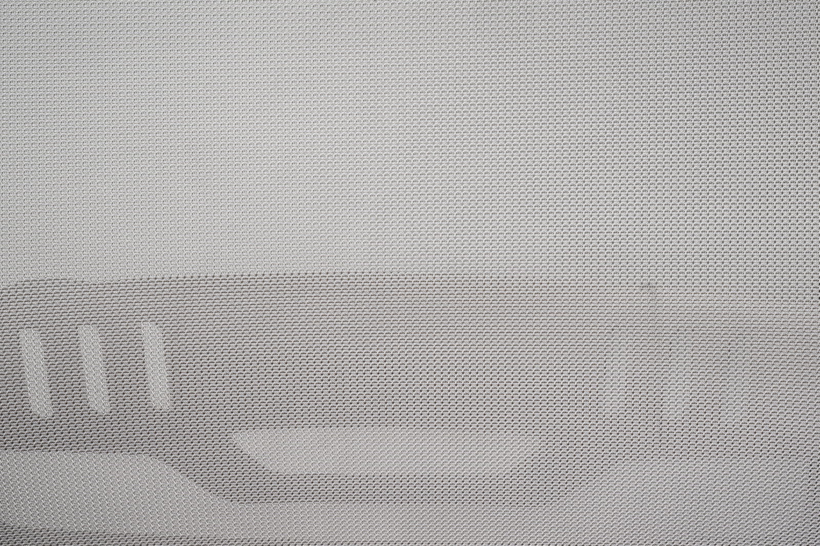 Nahaufnahme eines grauen Netzstoffs mit strukturiertem Muster, vermutlich Teil eines Drehstuhls, von vorne betrachtet.