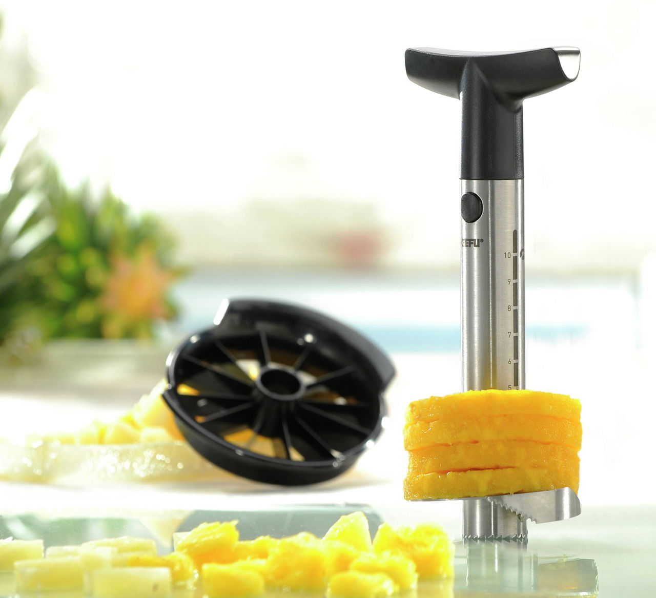 Ananasschneider Professional aus Edelstahl mit schwarzem Griff, der Ananasscheiben schneidet. Perspektive: seitliche Nahaufnahme.