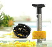 Ananasschneider Professional aus Edelstahl mit schwarzem Griff, der Ananasscheiben schneidet. Perspektive: seitliche Nahaufnahme.