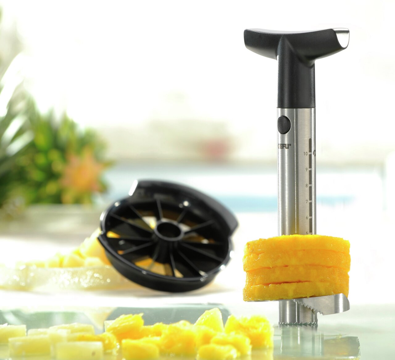 Ananasschneider Professional aus Edelstahl mit schwarzem Griff, der Ananasscheiben schneidet. Perspektive: seitliche Nahaufnahme.