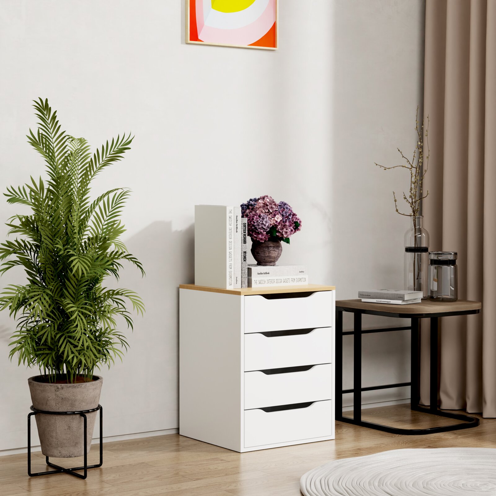 VCM Nachttisch MALIRA Modernes weißes Schubladen-Container/Kommode mit Holzplatte, dekoriert mit Büchern und violettem Blumenstrauß, im Wohnraum neben rundem Beistelltisch und Zimmerpflanze, Frontansicht leicht schräg von vorn