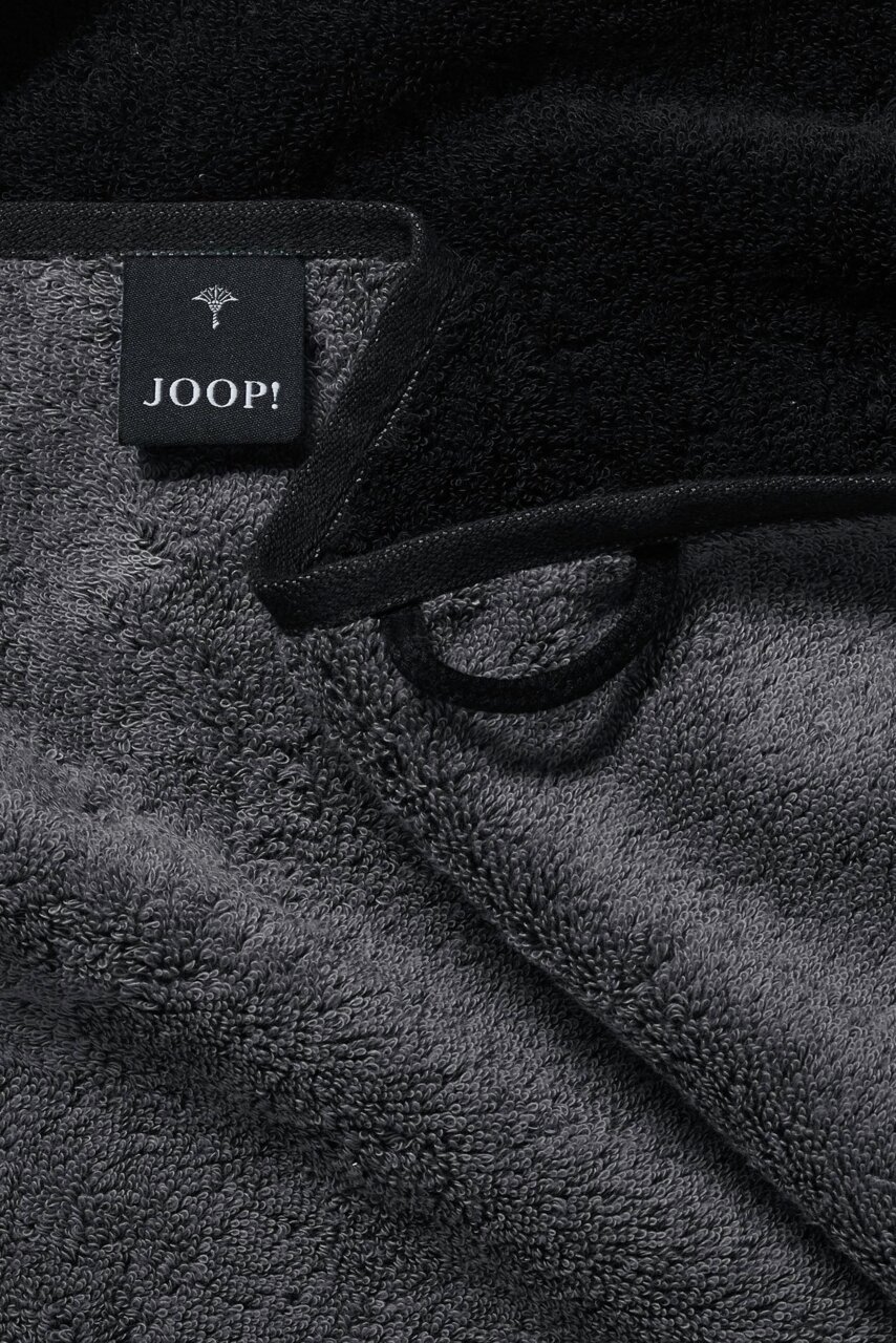Nahaufnahme eines grauen Handtuchs mit schwarzem Rand und einem Joop-Label.