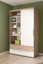 Schiebetürenschrank aus Holz mit weißer Tür, offene Regale mit grünen und weißen Körben, seitliche Perspektive