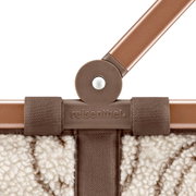 Detailaufnahme einer reisenthel Tasche/Korb in Braun-Beige mit Teddyfleece-Optik, braunem Griff und geprägtem reisenthel-Logo, frontale Nahansicht