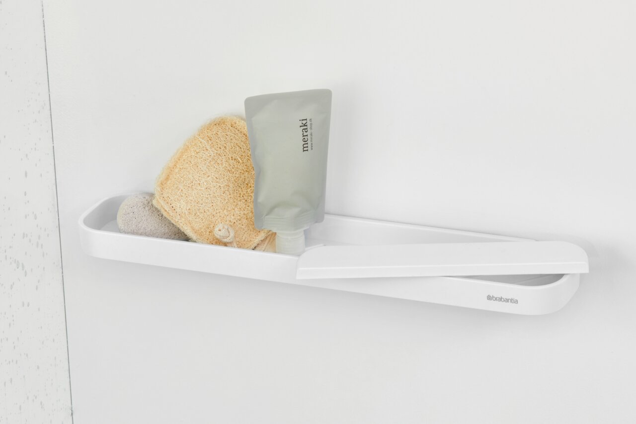 Weiße Duschablage an der Wand mit Pflegeprodukten und Schwamm, seitliche Perspektive