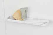 Witte doucheplank aan de muur met verzorgingsproducten en een spons, zijaanzicht