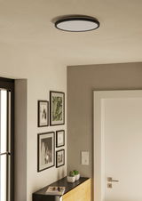 LED-Deckenleuchte ROVITO in einem modernen Raum von unten betrachtet, mit dekorativen Bildern an der Wand und einem Sideboard darunter.