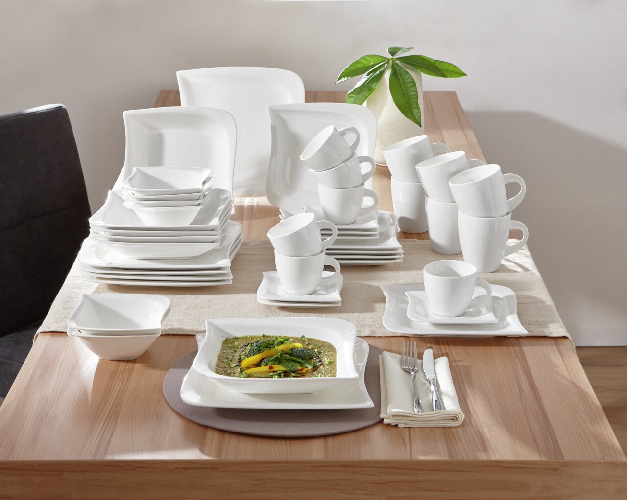 Elegantes weißes Kombiservice La Musica 42-tlg. auf einem Tisch, von oben betrachtet, mit Geschirr, Tassen und Besteck.