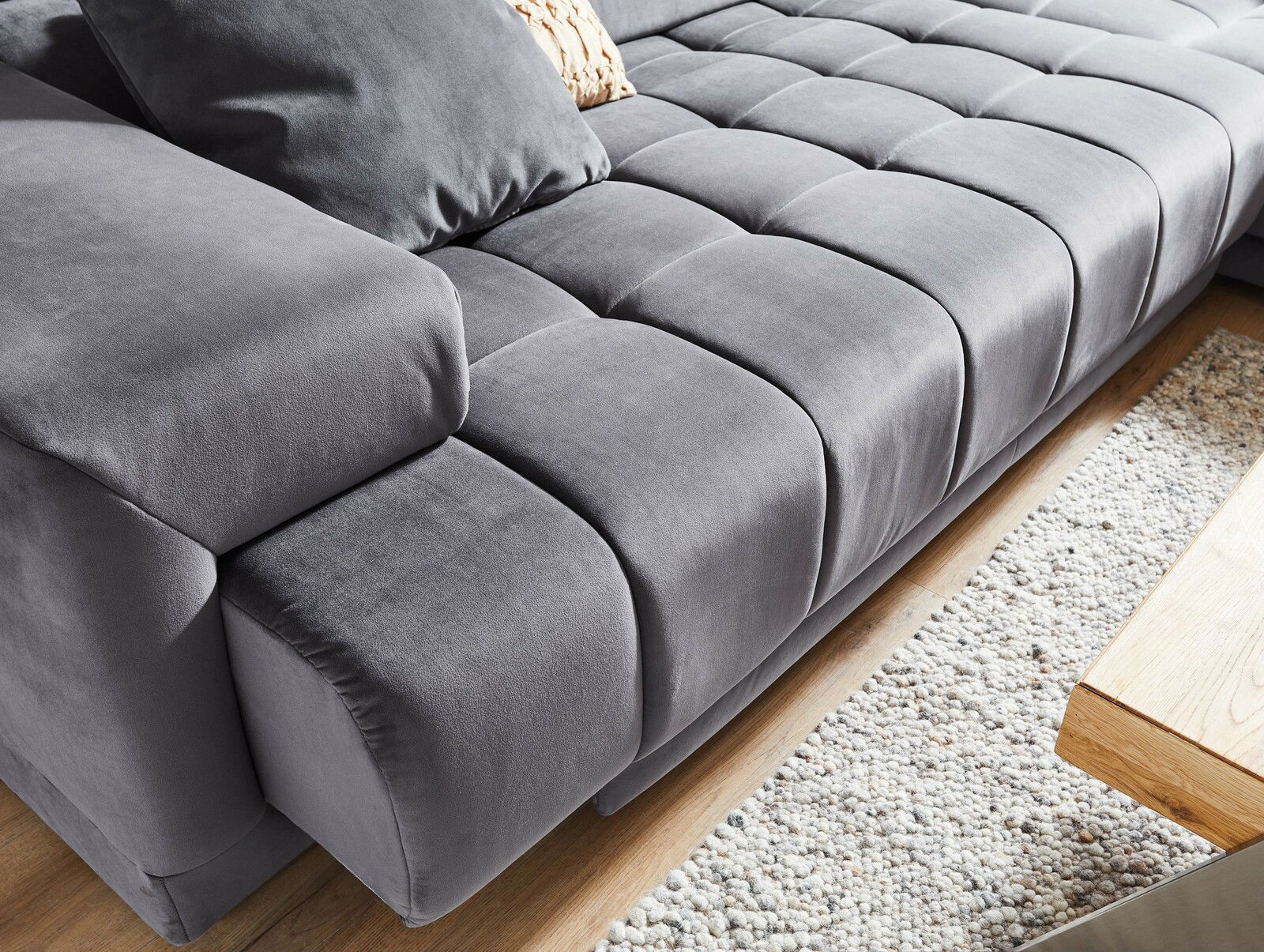 Graues Ecksofa mit weicher Polsterung und Kissen, Nahaufnahme von der Seite
