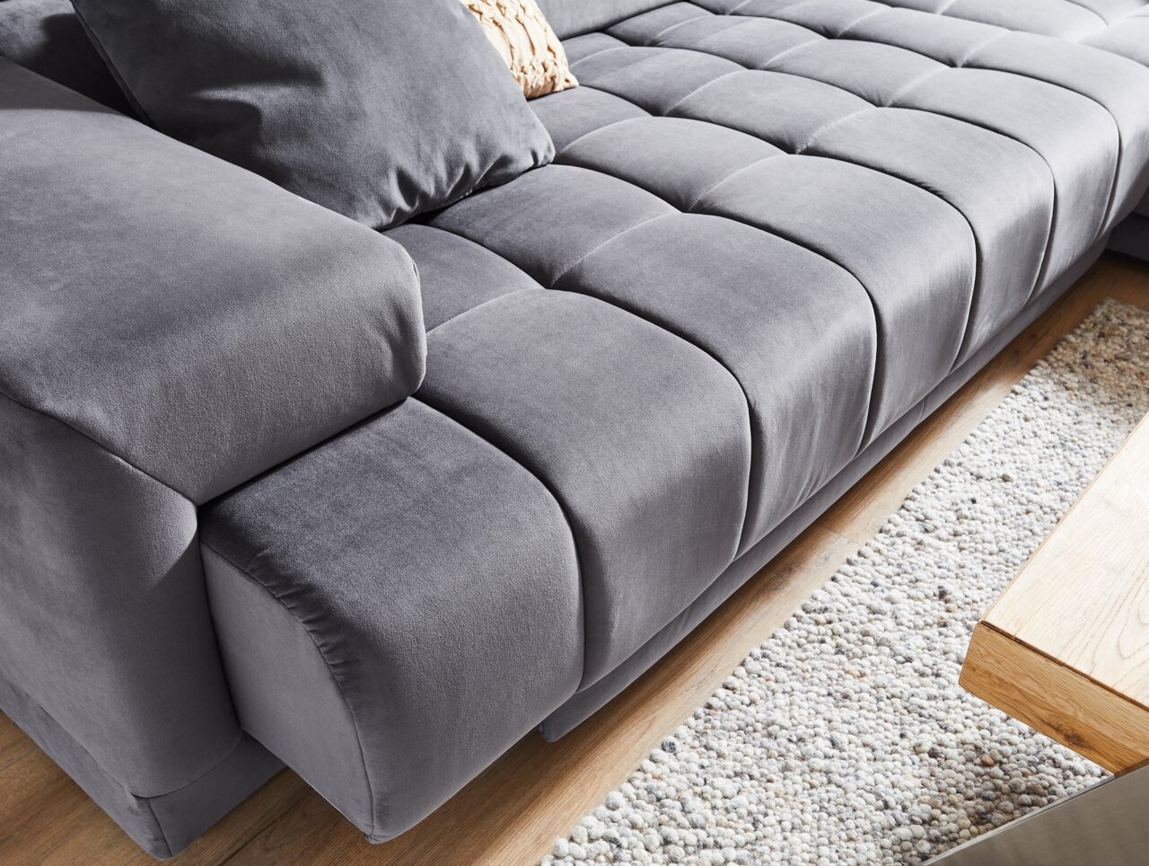 Graues Ecksofa mit weicher Polsterung und Kissen, Nahaufnahme von der Seite