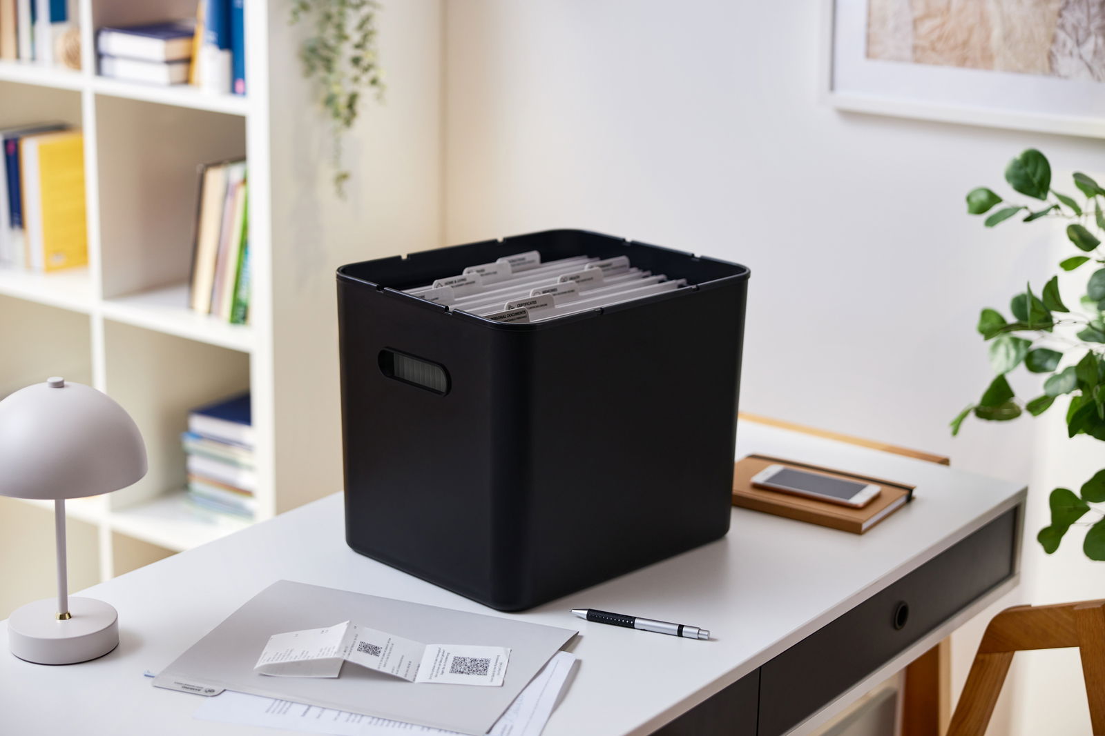 Schwarze Archivbox auf einem Schreibtisch, gefüllt mit Hängemappen, seitliche Perspektive