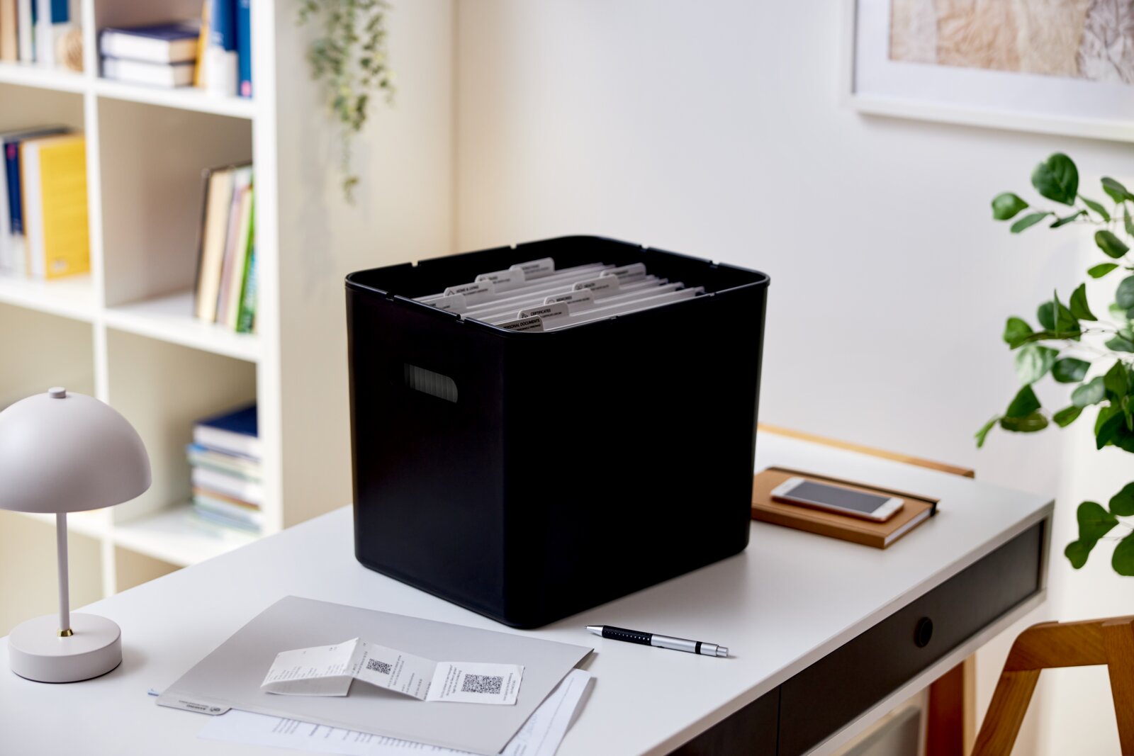 Schwarze Archivbox auf einem Schreibtisch, gefüllt mit Hängemappen, seitliche Perspektive