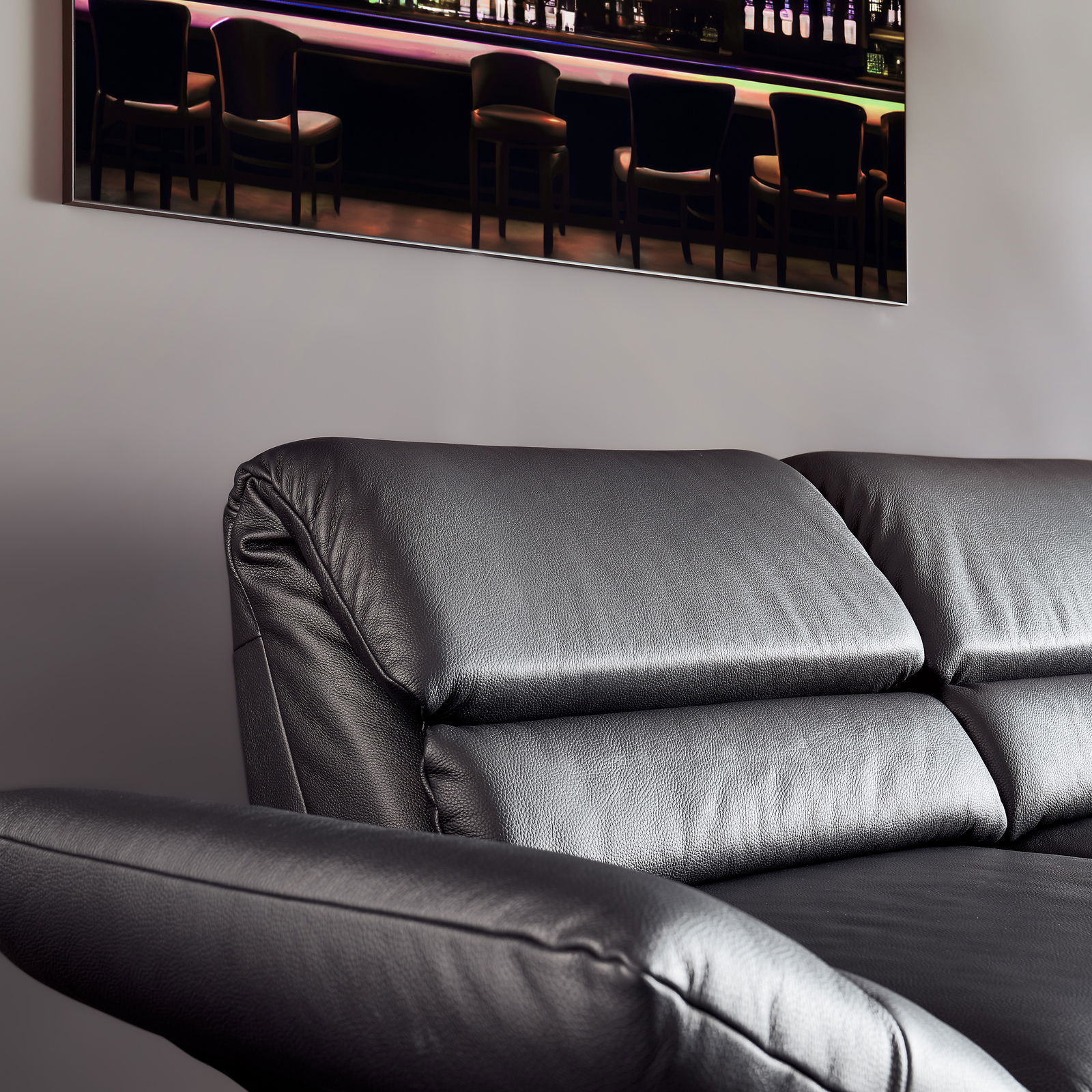 Schwarzes Ledersofa, Nahaufnahme von der Seite mit Blick auf die Rückenlehne und Armlehne.