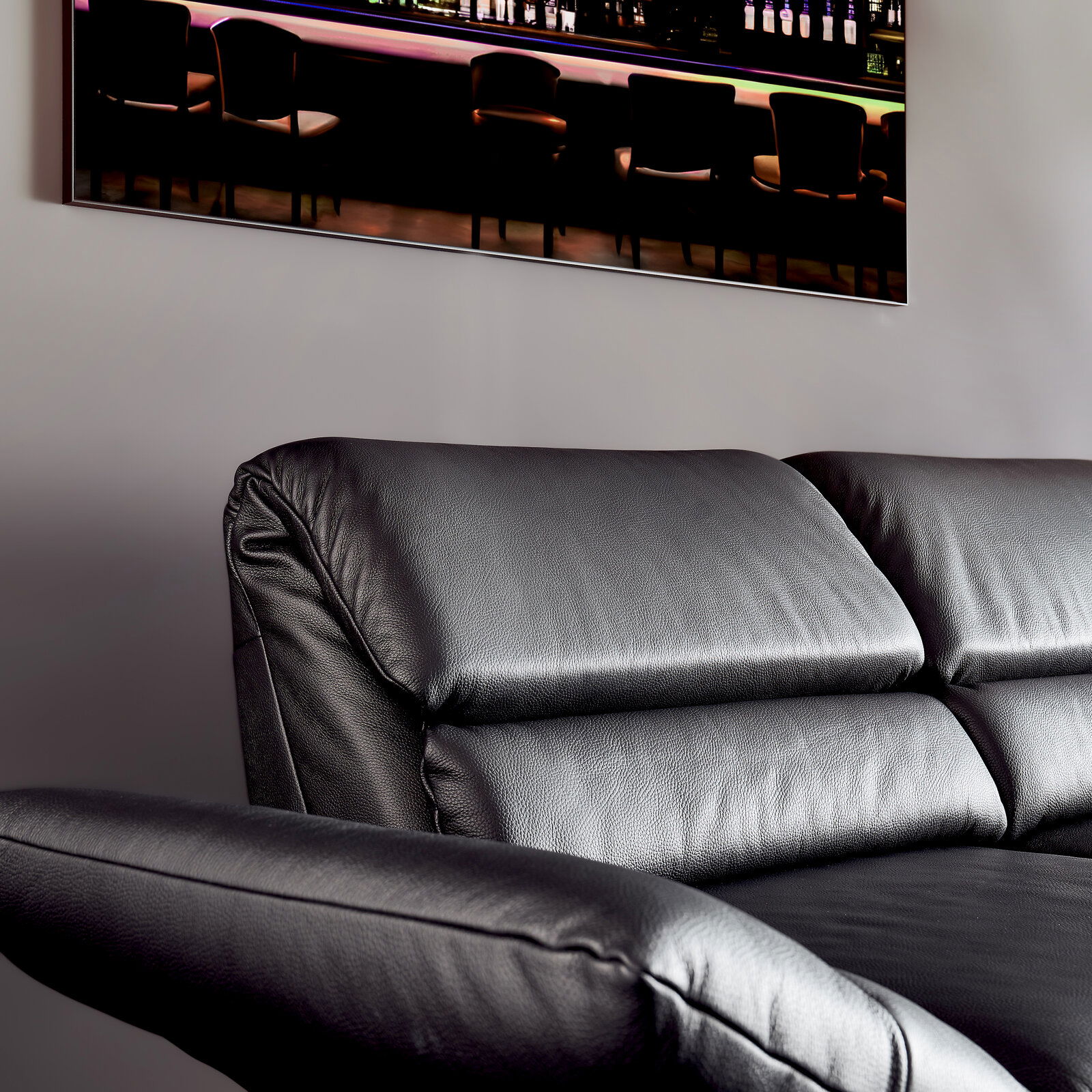 Schwarzes Ledersofa, Nahaufnahme von der Seite mit Blick auf die Rückenlehne und Armlehne.