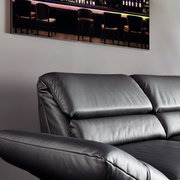 Schwarzes Ledersofa, Nahaufnahme von der Seite mit Blick auf die Rückenlehne und Armlehne.