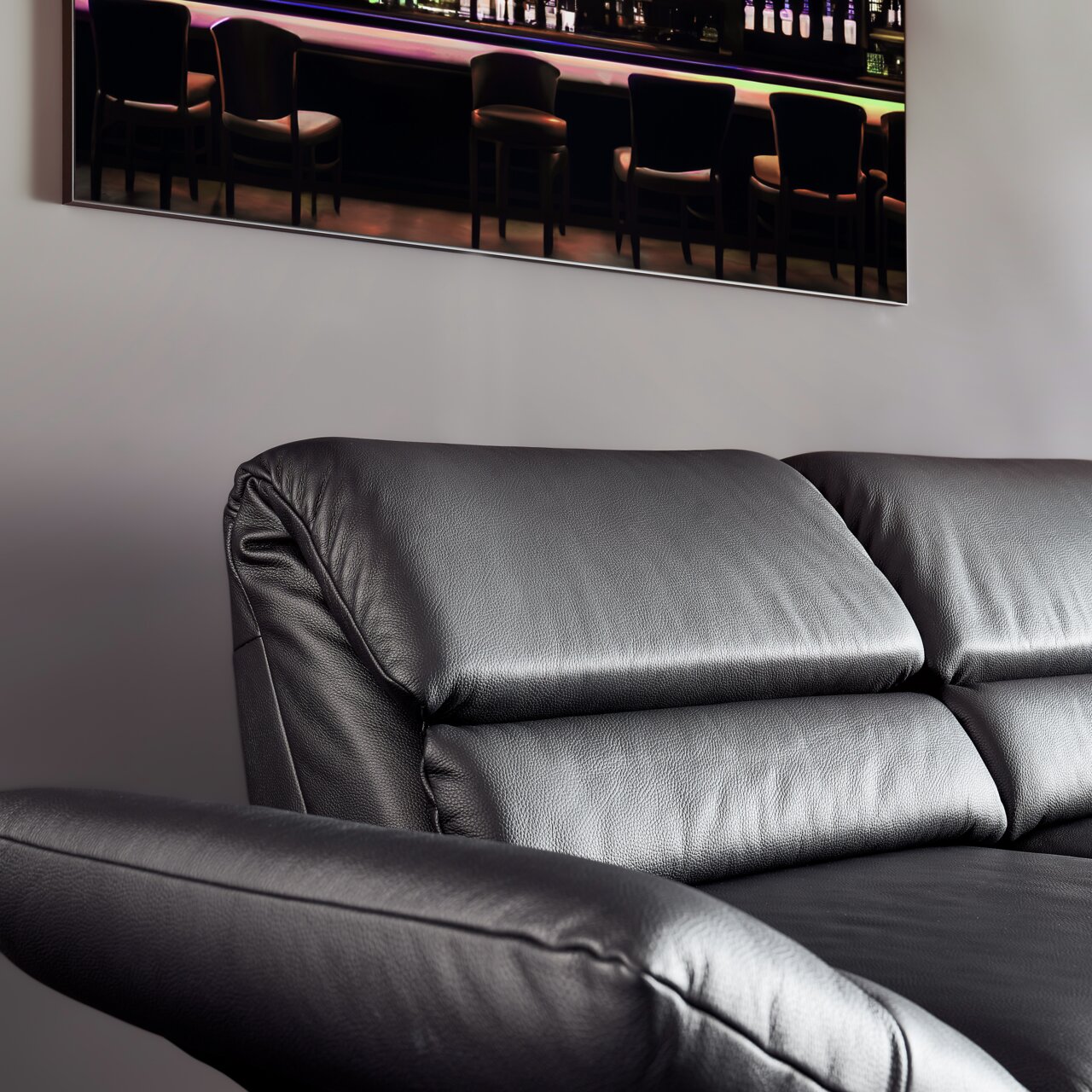 Schwarzes Ledersofa, Nahaufnahme von der Seite mit Blick auf die Rückenlehne und Armlehne.