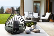 Dekoschale Giardino 25cm aus Glas und Metall mit Kerze und Steinen, im Vordergrund auf einem Tisch in einem modernen Außenbereich platziert, seitliche Perspektive